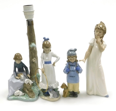 Four Nao porcelain figures, comprising girl in white nightgown yawning, 28cm high, girl in duffel coat with rucksack beside dog, 20cm high, girl with hoop beside dog, 28cm high, and a Nao table lamp base, of a young girl seated beside a tree trunk with ra