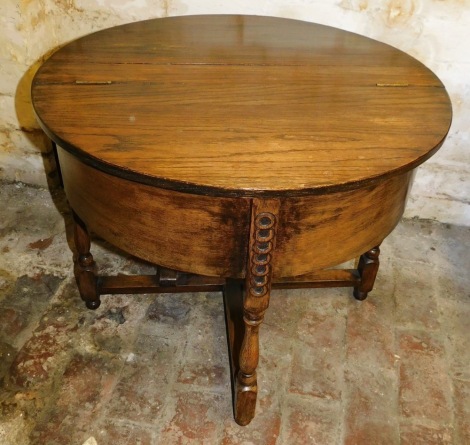 An early 20thC oak demi lune shaped work table, the hinged lid enclosing a fitted interior on turned supports, 53cm high, 64cm wide.