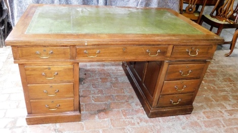 An early 20thC mahogany pedestal desk, the top with a green leather inset above an arrangement of nine drawers, each with brass drop handles, on a plinth, 76cm high, 153cm wide, 91cm deep.