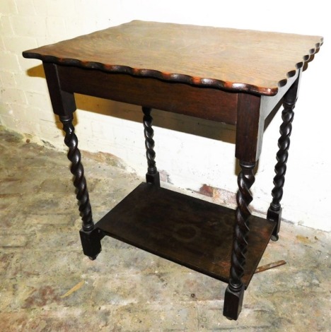 A 1920's oak two tier occasional table, rectangular top with a shaped edge, on spiral turned supports, united by an under shelf, 68cm high, 58cm wide.