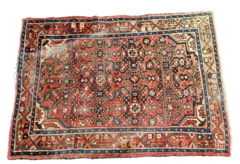 A Hamadan rug, decorated with geometric motifs against a red ground with various borders, 155cm x 106cm.