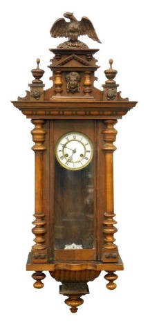 A 19thC walnut cased Vienna wall clock, the 12cm diameter dial with Roman numerals, fronted by an arch glass flanked by quarter columns, in a serpentine case with eight day movement, 66cm high.