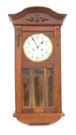 A 20thC oak wall clock, the 18cm diameter chrome plated face, with Arabic numerals, in a carved case with glazed front, 69cm high.