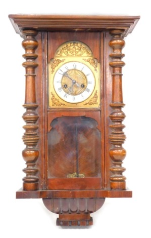 An early 20thC walnut Vienna wall clock, the domed 13cm diameter enamel dial with Roman numerals, with rasied spandrels flanked by quarter columns, in serpentine case, with pendulum, 56cm high. (AF)