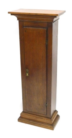 An oak pedestal cabinet, formed from a longcase clock case, on a plinth, 116cm high.