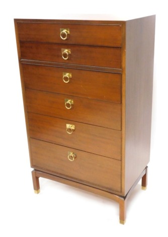 A G-Plan teak narrow chest, of six graduated drawers, each with brass ring handles on shaped stand with brass feet, stamped to second drawer, 117cm high, 69cm wide, 43cm deep.