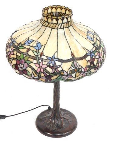 A Tiffany style desk lamp, the outswept cream domed floral shade with applied orange cabochon beads, on a leaf moulded base, 74cm high with shade, 48cm diameter.