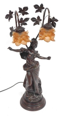 An Art Nouveau bronze effect table lamp, of a semi clad female, with fluted orange shades and vine supports, 79cm high.