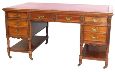 A Maple & Co of London walnut writing desk, with red leather inset top above arrangement of two pedestals each with three drawers and shelf and two central drawers with brass swing handles, carved and turned supports, 77cm high, 153cm wide, 89cm deep.