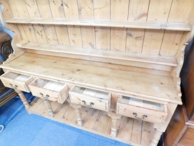 A rustic pine kitchen dresser, top with a moulded cornice and shelves above arrangement of four drawers with arched recesses and a pot board, on bun feet, 189cm high, 177cm wide, 42cm deep. - 2