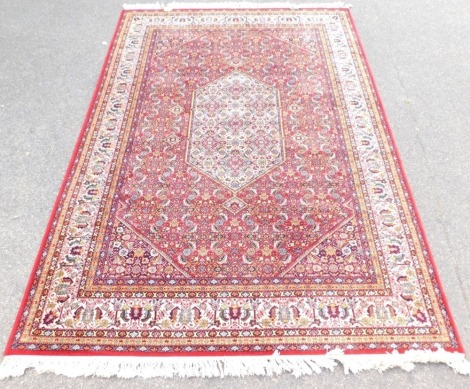 An Eastern rug, on a red floral ground, 293cm x 199cm.