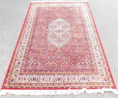 An Eastern rug, on a red floral ground, 293cm x 199cm.