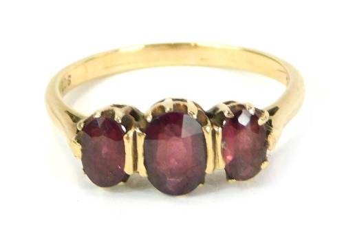 A garnet dress ring, set with three oval garnets in claw basket setting, on a yellow metal band, stamped 9ct, ring size L, 2.2g all in.