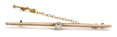 A diamond set bar brooch, with single round brilliant cut diamond, in claw setting on yellow metal bar, with safety chain, unmarked, the diamond approx 0.05 points, 6cm wide, 3.7g all in.