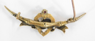 A Victorian bar brooch, wish bone backed with central heart and bowed design, set with garnet, yellow metal, stamped 15ct, 5cm wide, 2.7g all in. - 2