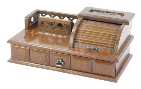 A 1960's desk form jewellery cabinet, with roll top finish and fret moulded top and single drawer, 16cm high, 32cm wide, 17cm deep.