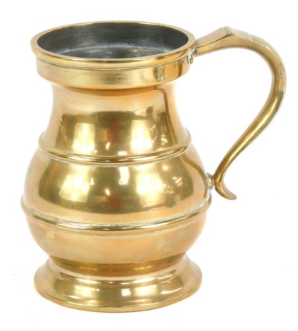 A brass quart tankard, with shaped handle and moulded bands, marked V R 29, 17cm high.