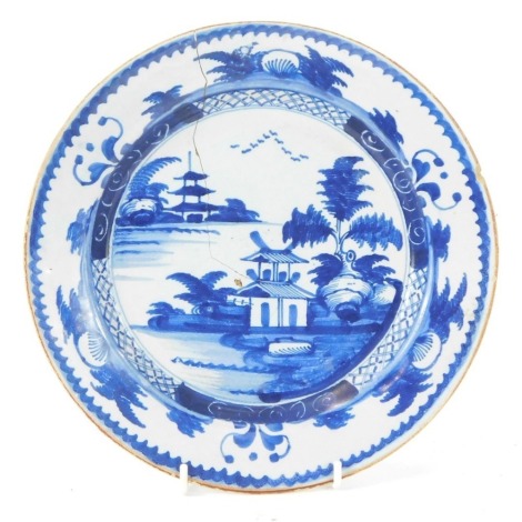 An 18thC Delft plate, decorated in blue with an Oriental landscape, 23.5cm diameter. (AF)