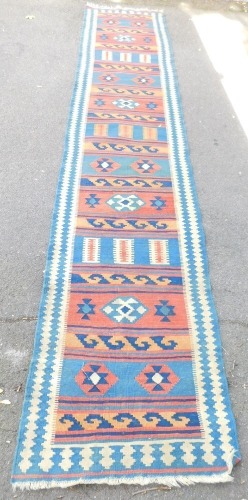 A Kashgai kilim rug, red, blue and green weave and knotted design, 387cm x 80cm.