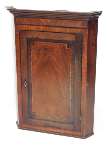 A 19thC mahogany corner cupboard, with moulded top and cross banded decoration and bone escuteon, 106cm high, 68cm wide, 48cm deep.