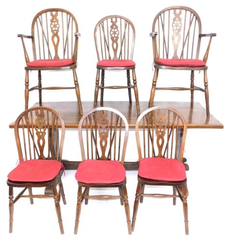 An oak refectory table, on trestle base, 73cm high, 182cm wide, 82cm deep, with set of six wheel back chairs. (7)