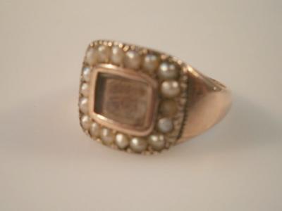 A 19thC memorial ring with hair insert to front surrounded by seed pearls