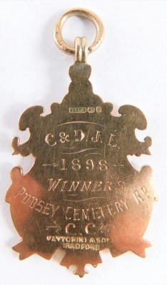 A Victorian 9ct gold fob, with scroll outline, centred by a shield, marked verso C & D J L 1898 Winners Pudsey Cemetery Rd C. C., 5cm high, 8g. - 2