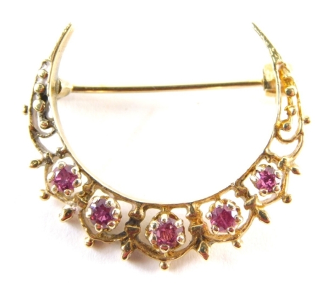 A crescent moon brooch, set with five rubies in claw setting with filigree type detail, yellow metal, unmarked, and single pin back, 3cm diameter, 4.1g all in.