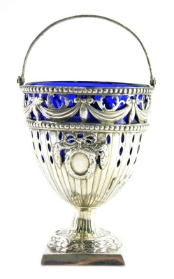 A George III silver plated Neo-Classical design basket, with swing handle, the body pierced with garlands and raised with orbs, on an inverted stem with square foot and blue glass liner, London 1774, maker AB, 3.14oz, 11cm high.