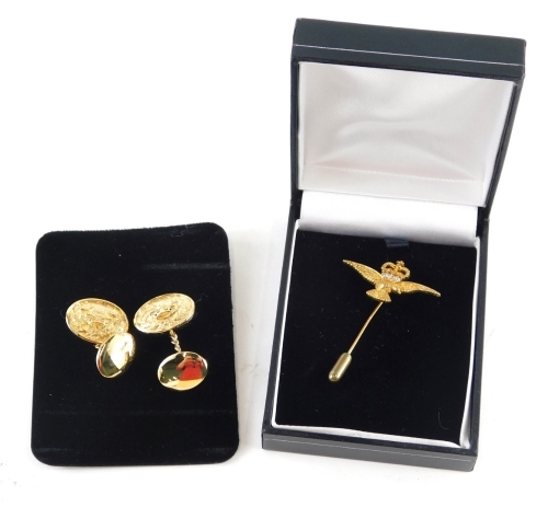 A cap badge of an eagle mounted with crown, set with paste stones, 5cm high, and a pair of gold plated crown cuff links. (2)