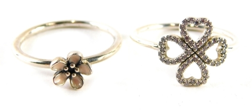 Two Pandora dress rings, comprising one with pink enamel flower, ring size S and a white stone set four leaf clover, rings size S½, each white metal stamped 925, 4.6g, boxed.