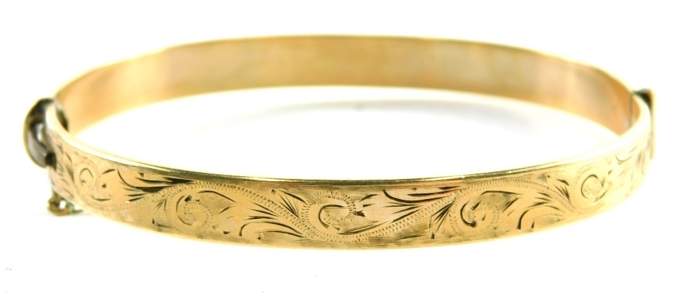 A hinged bangle, with foliate scroll design, marked one 5th 9ct gold ...