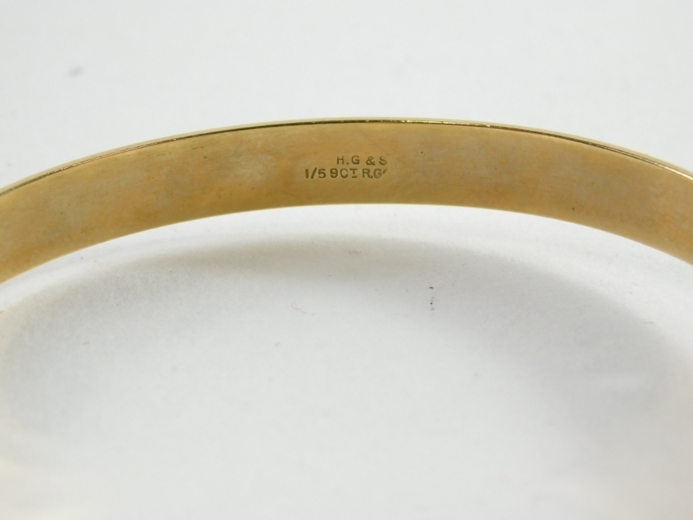 A hinged bangle, with foliate scroll design, marked one 5th 9ct gold ...