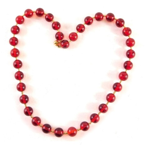 A cherry amber coloured necklace, with spherical beads 1.5cm wide, 58cm long.