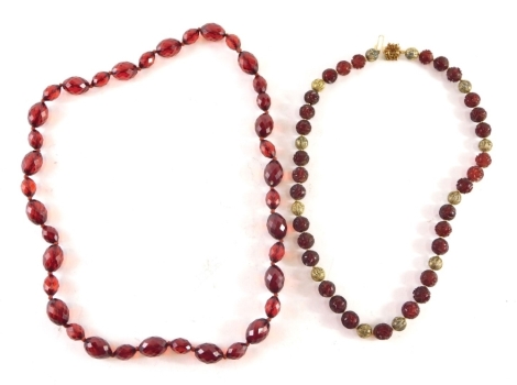 Two carved and faceted red amber necklaces, comprising a faceted example, 70cm long and a carved example with filigree decoration and flower clasp, 52cm long. (2)