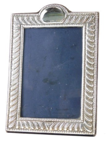 An Elizabeth II silver photograph frame, with vacant cartouche, repousse decorated with velvet lined easel back, London 1991, 20cm high.