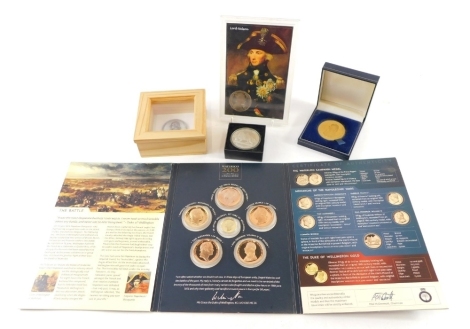 A Tower Mint gold plated commemorative Trafalgar medal, 5cm diameter, cased with paperwork, a Battle of Waterloo, plated with platinum layer Duke of Wellington medal, Battle of Waterloo commemorative coins, reproduction Nelson medal, and another Gibraltar