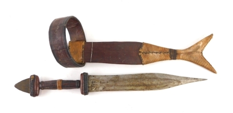 An Eastern dagger, with fish shaped scabbard, turned leather handle and metal arrowhead pommel, 46cm long.