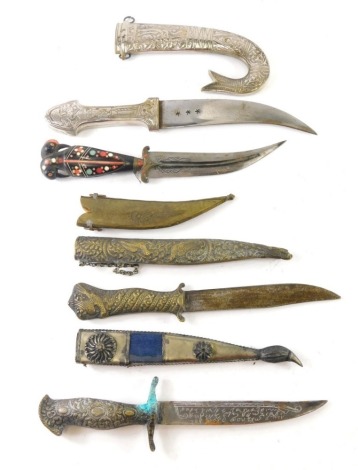 An Eastern brass dagger, with heavily decorated scabbard, plain blade and turned handle, 33cm long, and a quantity of other Eastern daggers and knives. (4)