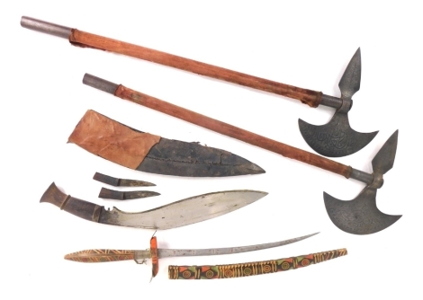 Various weaponry, a curved Eastern short sword with wooden scabbard, a pair of axes with turned cylindrical handles, 64cm high, and a Kukri. (a quantity)