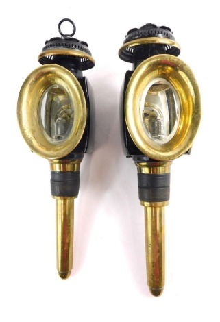 A pair of early 20thC brass carriage lanterns, with black metal highlights, with oval front glass sections, on turned stems, 41cm high.