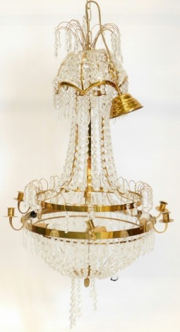 A 20thC cut glass and metal framed chandelier, of classical design, the circular frame raised with lion's mask and Egyptian head figures, with fixed candle sconces and enriched with a succession of cut glass drops, octagonal pieces and other glass sectio