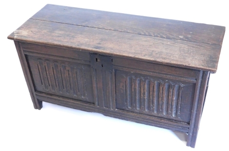 A late 18th/early 19thC oak coffer, with a two planked top above a panel front with fluted carving, on stiles, 57cm high, 115cm wide.