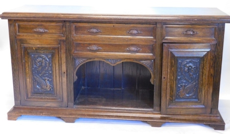 An early 20thC oak sideboard, the top with a moulded edge above an arrangement of four drawers, each with shell shaped handles, and a recess flanked by two carved panelled doors on tapering feet, 99cm high, 194cm wide, 58cm deep.