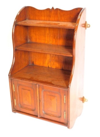 A walnut wall cabinet, with a shaped top and sides, two shelves and two panelled doors, 76cm high, 46cm wide.