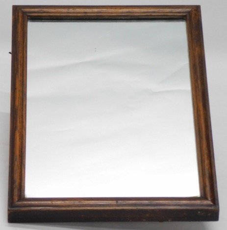 A late 19thC oak dressing mirror, with a moulded frame, the back mounted with a heavy duty industrial type or shaving wall mounting pivot, the mirror 60cm x 41cm.