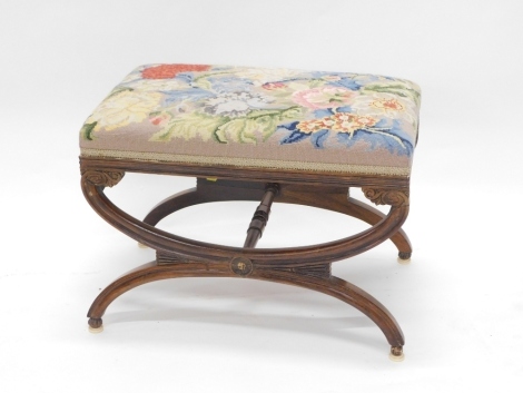 A Victorian rosewood stool, with a later floral woolwork padded seat on X shaped supports. 65cm wide