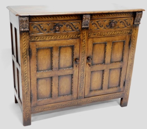 An oak side cabinet, the rectangular top with two carved frieze drawers and two panelled doors on stiles, possibly Titchmarsh and Goodwin, 101cm high, 117cm wide