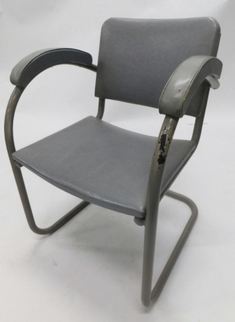 An industrial grey armchair, with grey leather padded seat, arms and back, and tubular metal frame. The upholstery in this lot does not comply with the 1988 (Fire & Fire Furnishing) Regulations, unless sold to a known exporter or upholsterer it will be 