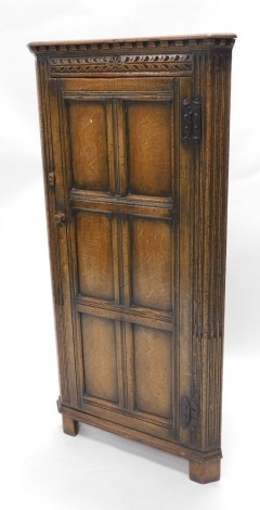 An oak free standing corner cupboard, in the manner of Titchmarsh & Goodwin, with panelled doors, 138cm high, 67cm wide, 60cm deep.